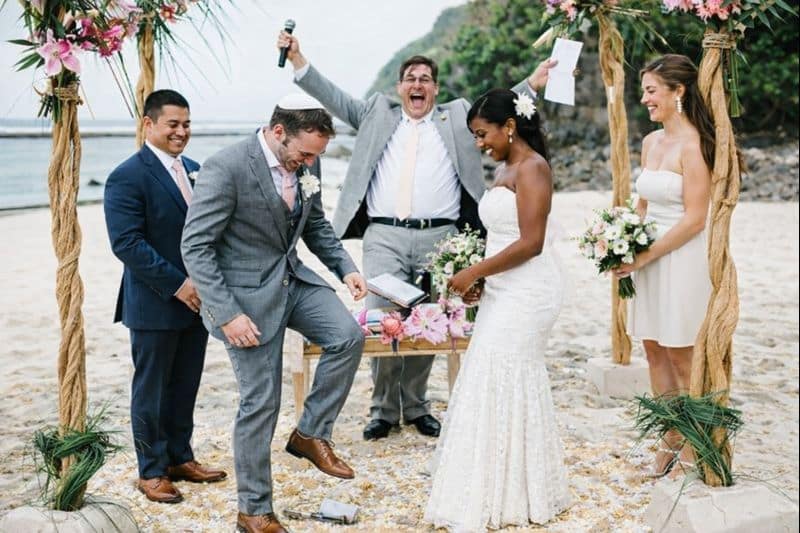 African American bride and Jewish groom breaking the glass during a destination beach wedding ceremony